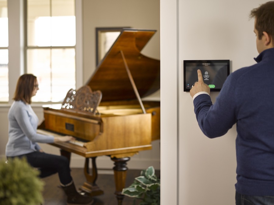 A person using a Control4 interface as someone plays piano in the background.