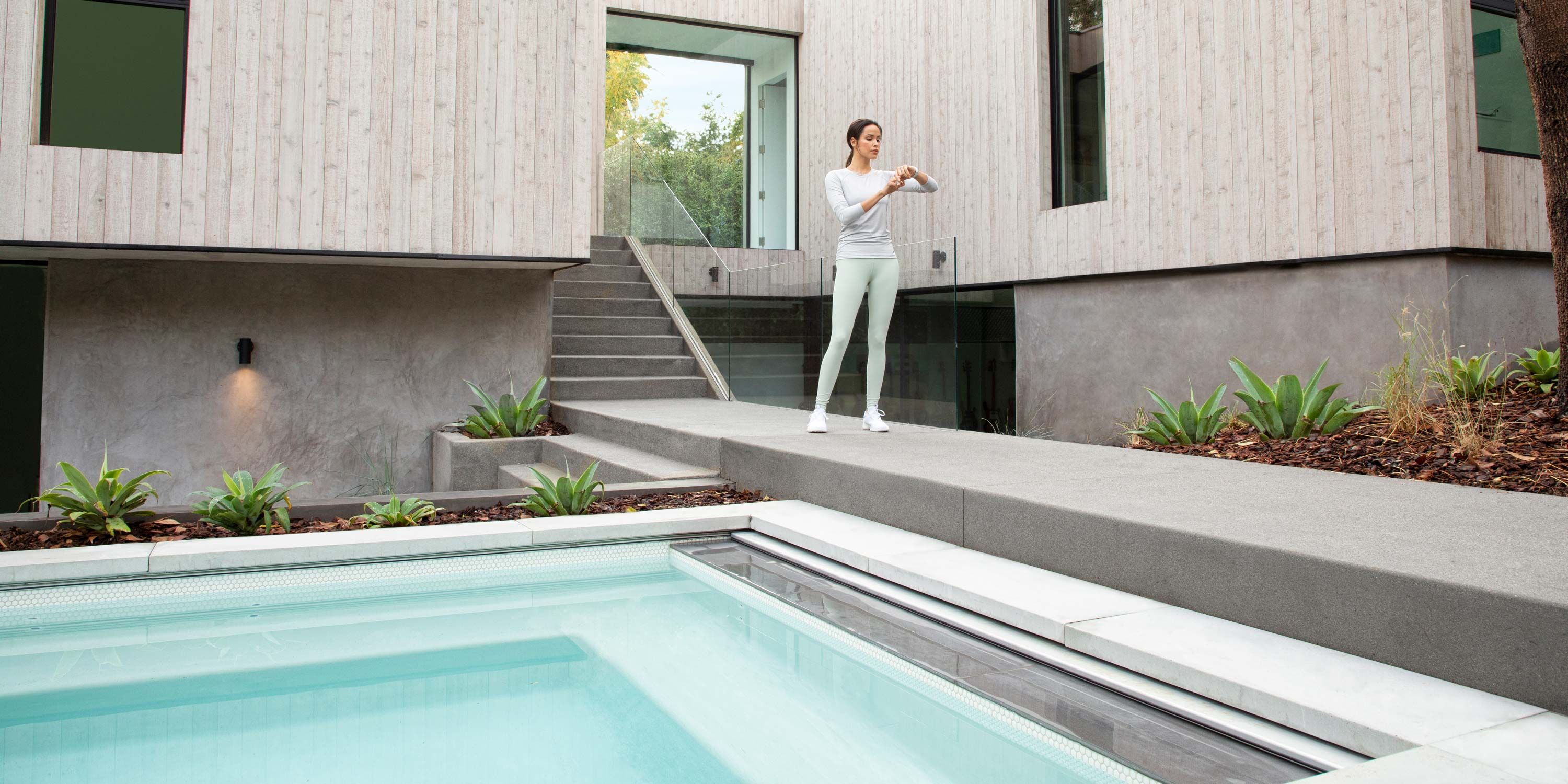 woman checking watch and standing outside by pool